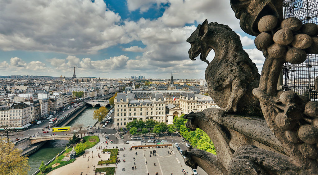 A Notre Dame de Paris Cathedral gargoyle looks west over the Seine River toward the Eiffel Tower